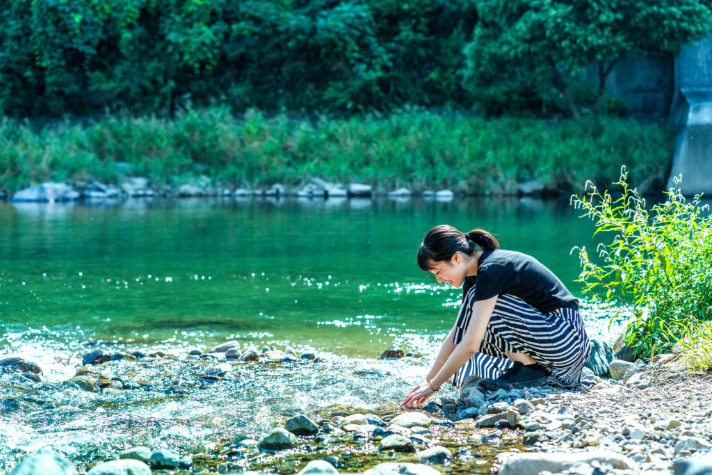 川辺で水に触れる女性